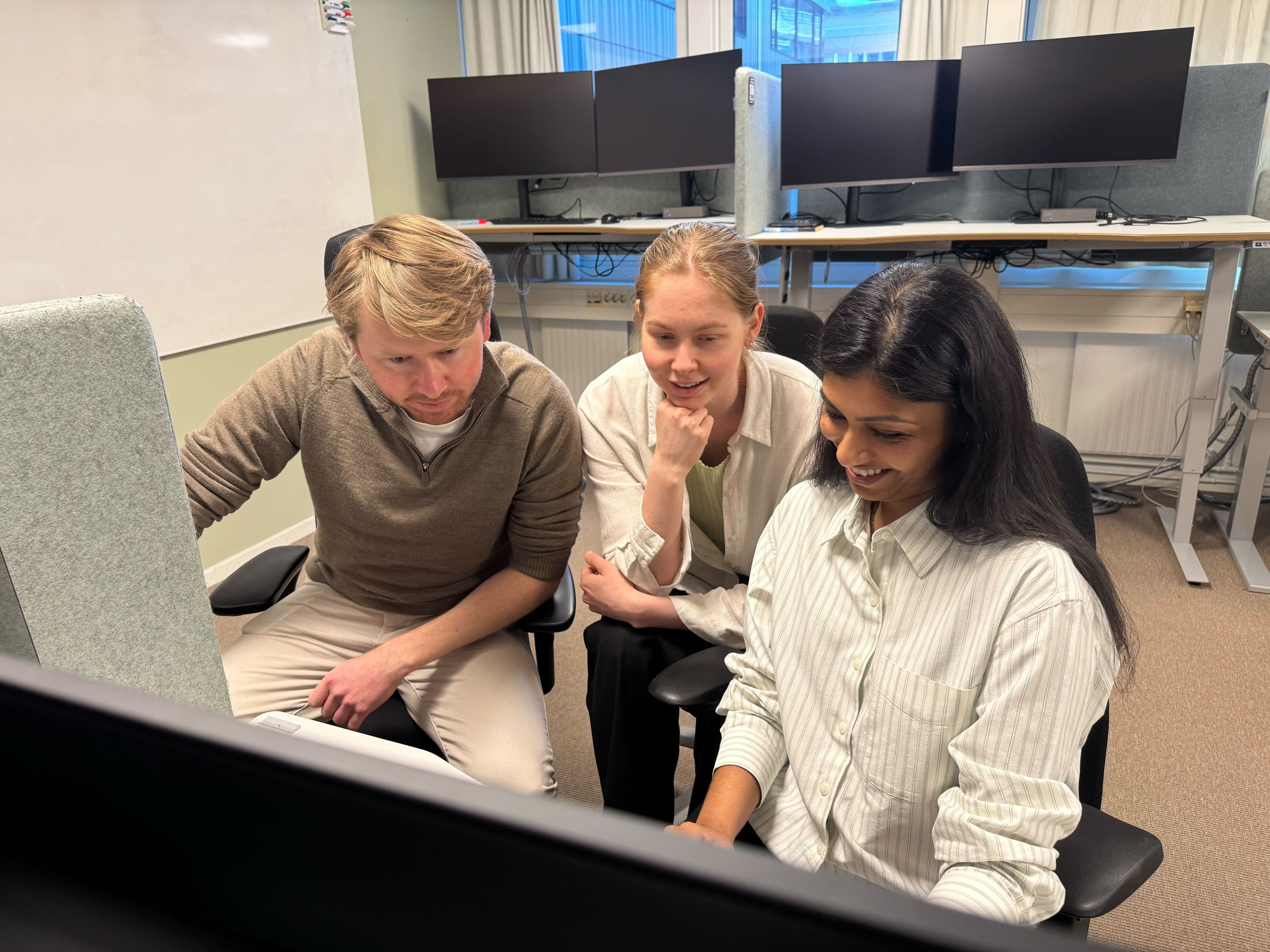Gaute, Nivethika og Jenny sitter foran en PC-skjerm i kontorlokalet,
