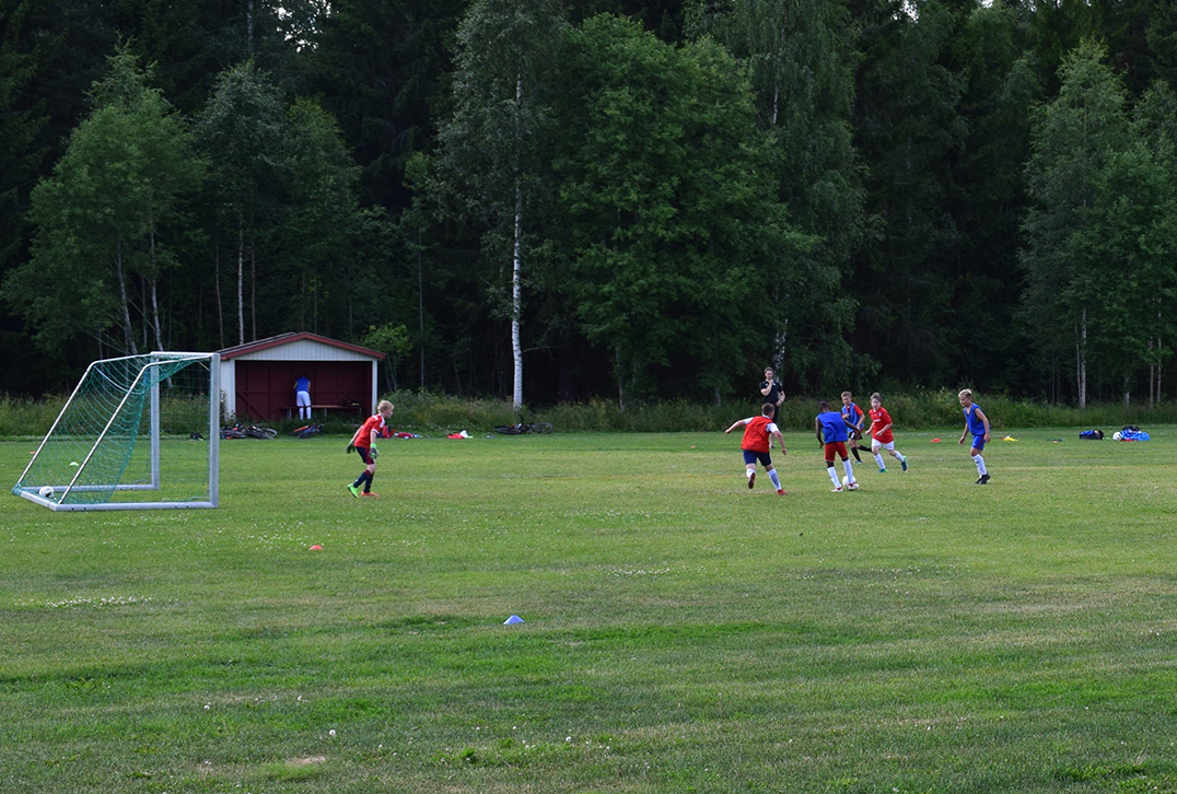 Barn spiller fotball ute på gressmatte.