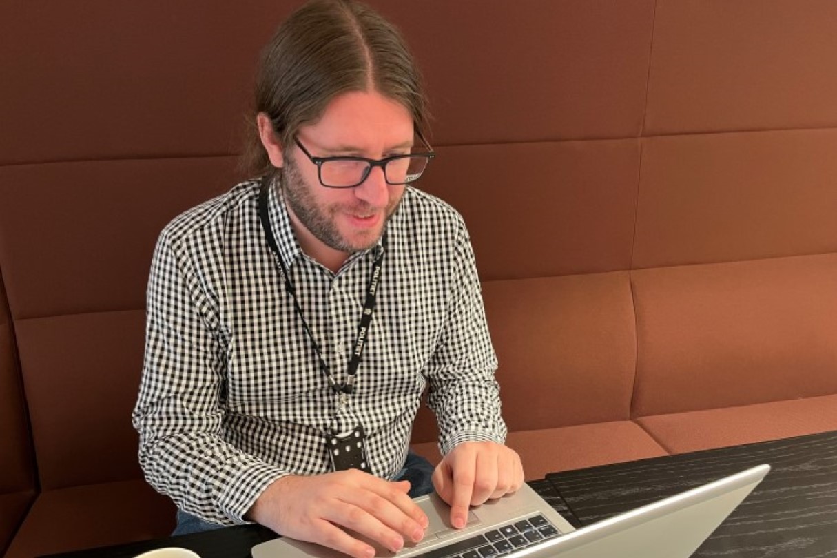 Roger Karlson som sitter foran en PC i en rød sofa.